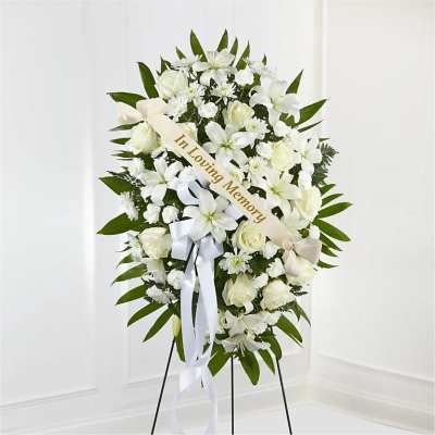 White funeral standing spray with roses and lilies on an easel