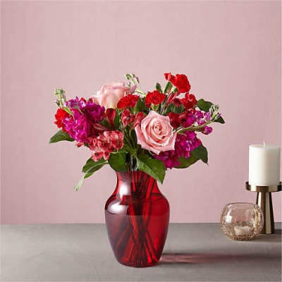Pink and red flower arrangement in a red glass vase