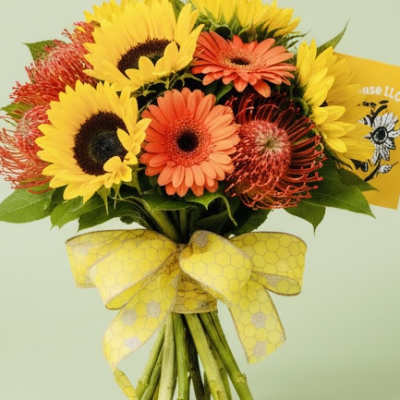 Bouquet of sunflowers and orange gerbera daisies tied with a yellow ribbon