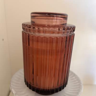 Amber glass jar candle with a matching lid on a white pedestal