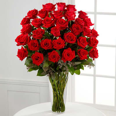 Tall bouquet of red roses in a clear glass vase