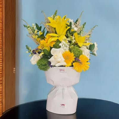 Yellow lilies and white roses in a white gift box arrangement