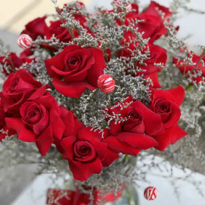 Red roses arranged in a glass vase with silver filler and ribbon