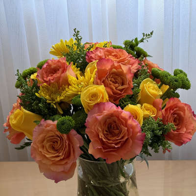 Bouquet of orange and yellow roses with yellow chrysanthemums in a glass vase