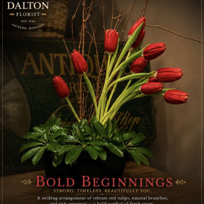 Arrangement of red tulips in a black container with branches