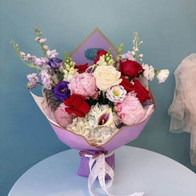 Bouquet of red, pink, white, and purple flowers wrapped in lavender paper