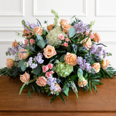 Large pastel floral arrangement with peach roses, lavender blooms, and green hydrangeas