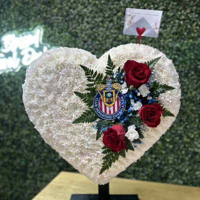 Heart-shaped white floral arrangement with red roses on a stand