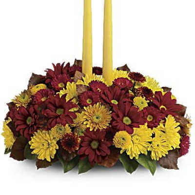 Red and yellow flower centerpiece with two tall yellow candles