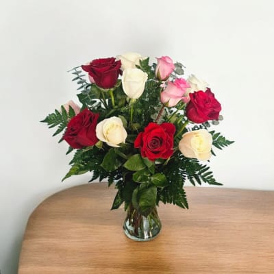 Bouquet of red, pink, and white roses in a clear glass vase