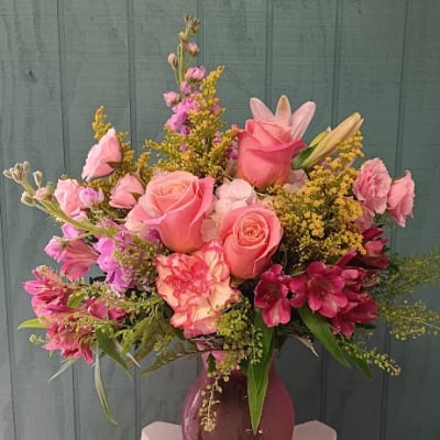 Pink roses and mixed flowers arranged in a purple vase