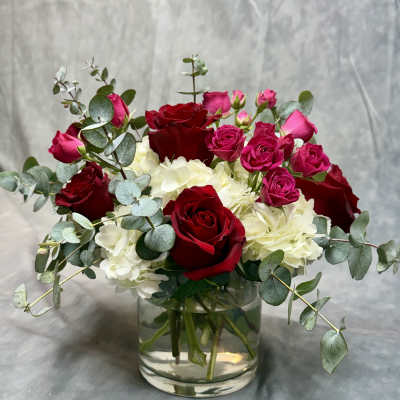Red and pink roses with white hydrangeas in a glass vase