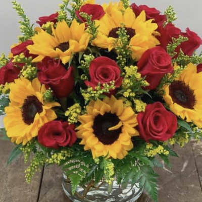 Bouquet of red roses and yellow sunflowers in a glass vase