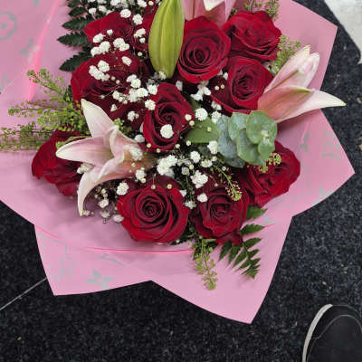 Bouquet of red roses and pink lilies wrapped in pink paper