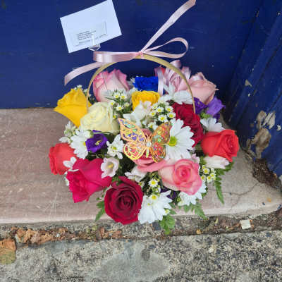 Mixed rose bouquet in a ribboned basket with white daisies