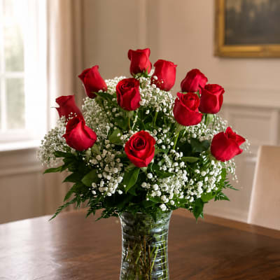 Red roses arranged in a clear glass vase with white filler flowers