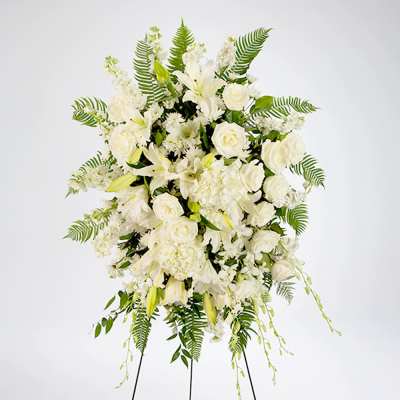 Tall white floral standing spray with roses and lilies on a black easel