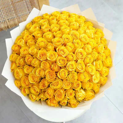 Large bouquet of yellow roses wrapped in white paper