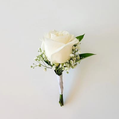 White rose boutonniere with baby's breath and green leaves
