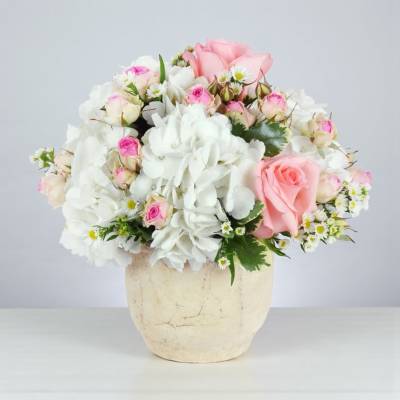 Pink and white rose bouquet in a cream vase