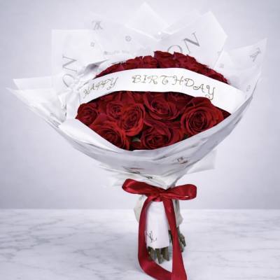 Bouquet of red roses wrapped in white paper with a red ribbon