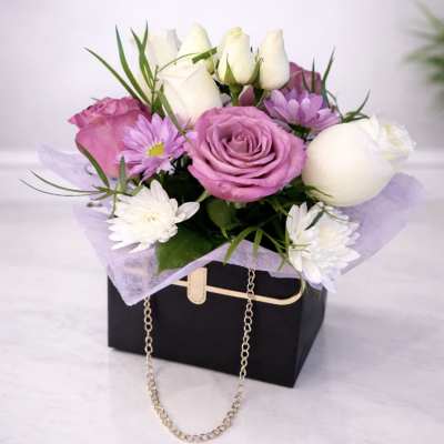 Pink and white roses with small daisies in a black gift box