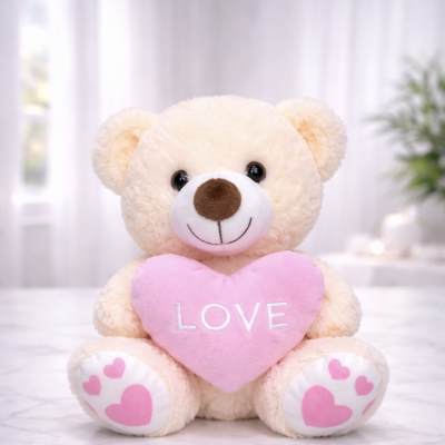 Plush teddy bear holding a pink heart with the word LOVE