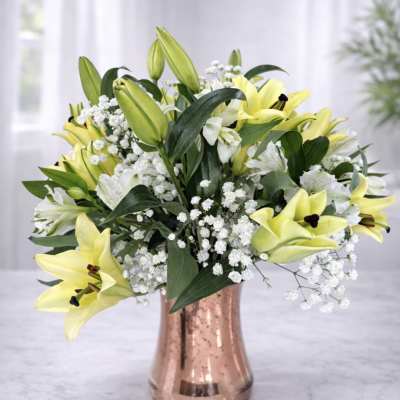 Yellow lilies and white baby's breath in a copper vase