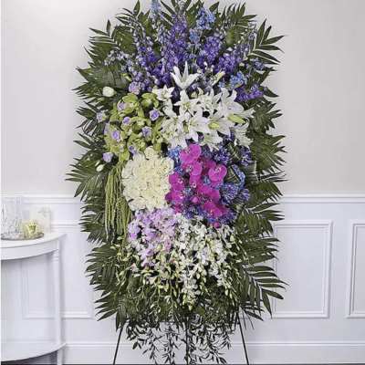 Standing floral spray with white lilies, orchids, and purple blooms