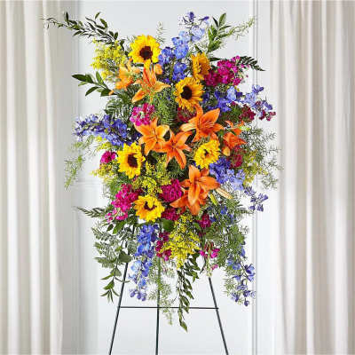 Tall standing floral spray with sunflowers, lilies, and blue flowers