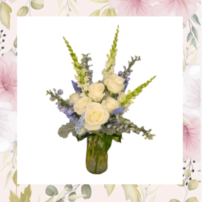 White roses and blue flowers arranged in a glass vase