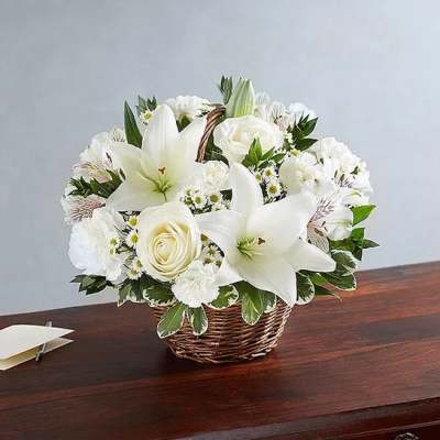 White lilies and roses arranged in a wicker basket