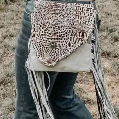 Patterned leather fringe bag worn over jeans outdoors