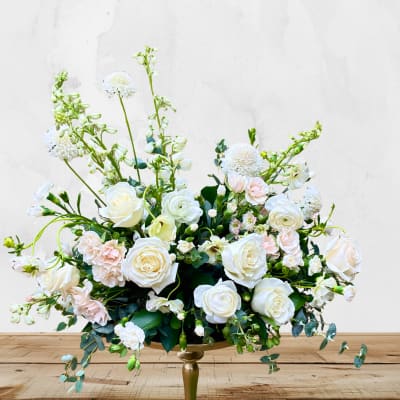 White and blush floral arrangement in a gold pedestal vase