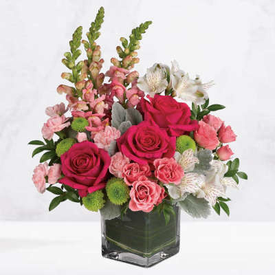 Pink roses and white alstroemeria in a clear square vase