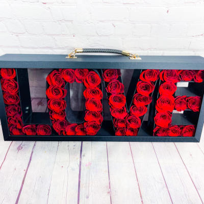 Black box with red roses arranged to spell LOVE
