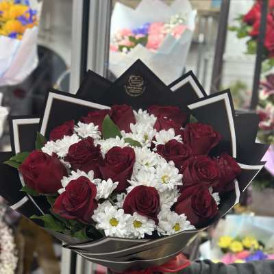 Bouquet of red roses and white daisies wrapped in black paper