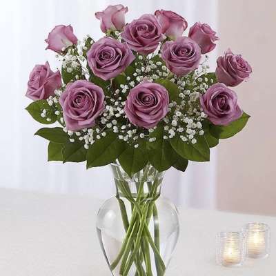 Lavender roses arranged in a clear glass vase with baby's breath