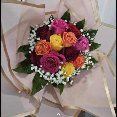 Bouquet of multicolored roses wrapped in pale pink paper