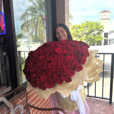 Woman holding a large bouquet of red roses wrapped in cream paper