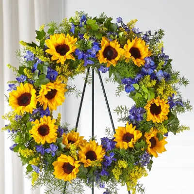Sunflower wreath with blue flowers on a black stand