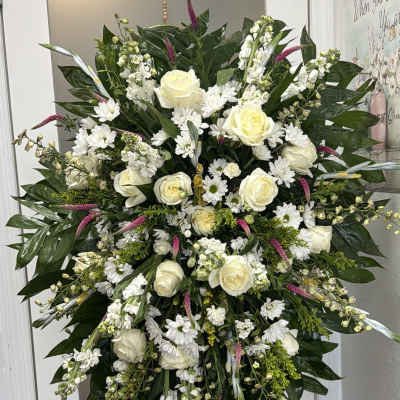 Large white floral standing spray with roses and daisies on an easel