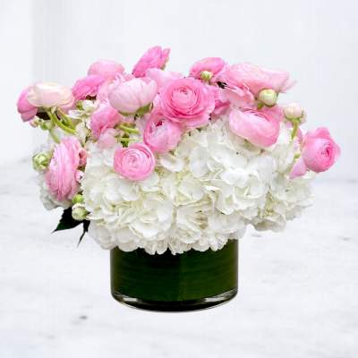 Pink ranunculus and white hydrangeas in a green glass vase