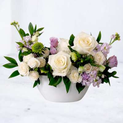 White and lavender roses arranged in a white bowl vase