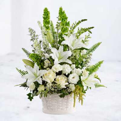 White lilies and roses in a white woven basket with green accents