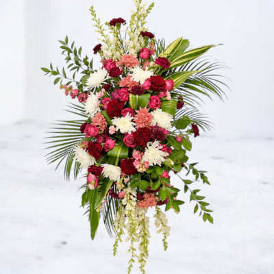 Tall floral arrangement with red, pink, and white blooms