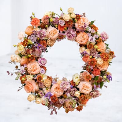 Circular floral wreath with peach, lavender, and orange blooms