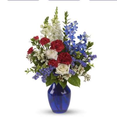 Red and white roses with blue flowers in a cobalt vase