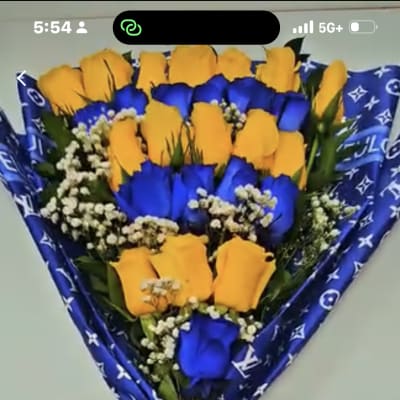 Bouquet of yellow and blue roses wrapped in patterned blue paper