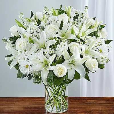 White lilies and roses arranged in a clear glass vase